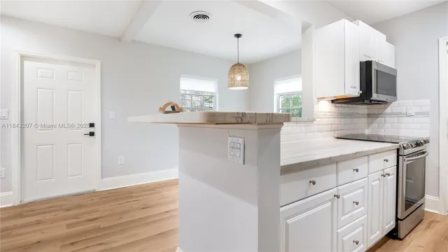a kitchen with kitchen island granite countertop a sink stove and wooden floor