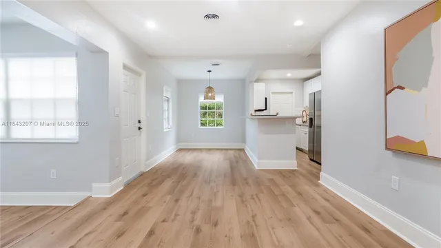 a view of a kitchen with wooden floor a sink a refrigerator and window