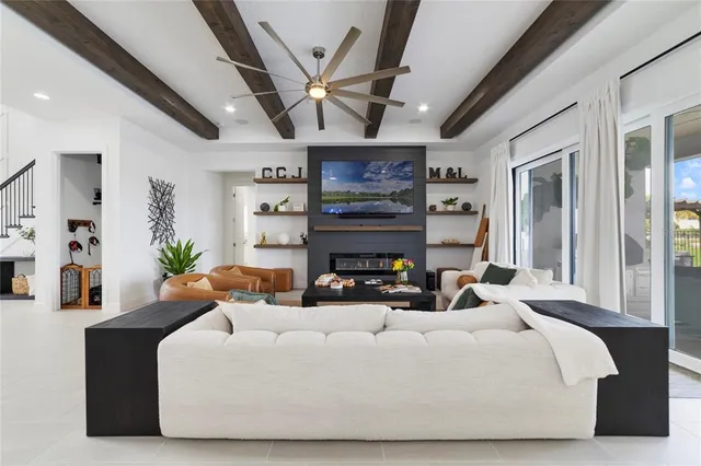 a living room with furniture kitchen view and a chandelier
