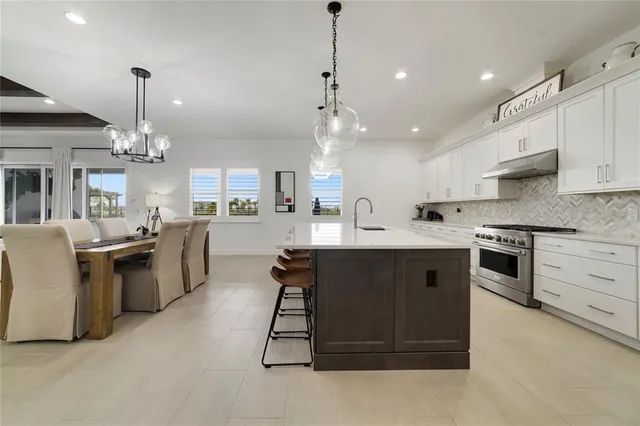 a large white kitchen with a refrigerator a sink dishwasher a stove and white cabinets with wooden floor