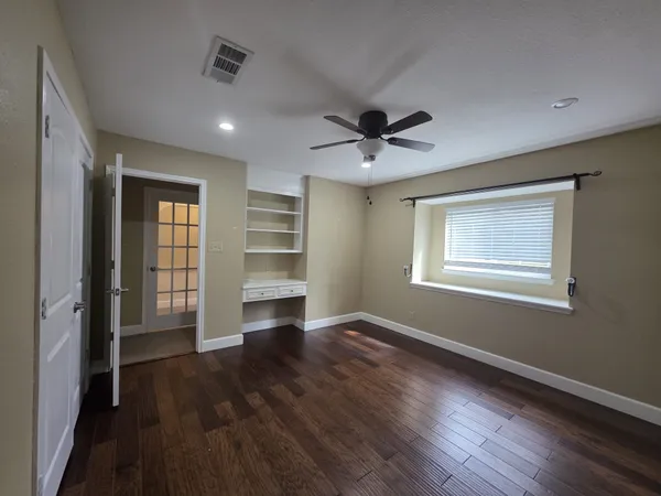 a view of an empty room with a window and wooden floor