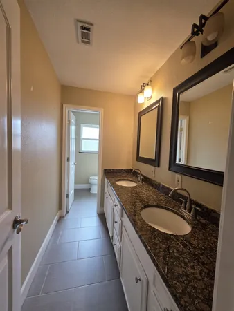 a spacious bathroom with a granite countertop sink a mirror and a shower