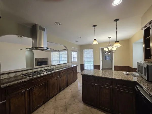a kitchen with kitchen island granite countertop a sink and a stove