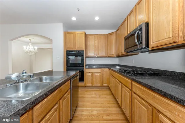a kitchen with stainless steel appliances granite countertop a sink a stove and a wooden cabinets