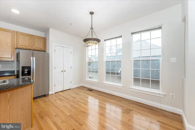 a view of an empty room with a window and kitchen view