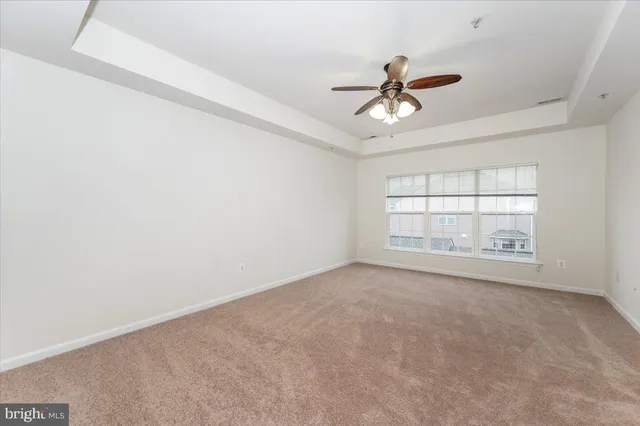 an empty room with windows and ceiling fan