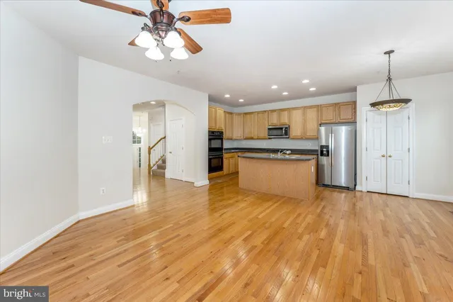 a kitchen with stainless steel appliances granite countertop a refrigerator a stove oven a sink dishwasher and a refrigerator with wooden floor