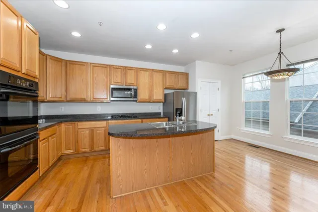a kitchen with stainless steel appliances granite countertop a sink a stove and a wooden floors