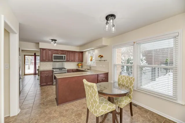 a kitchen with stainless steel appliances granite countertop a stove top oven a sink a dining table and chairs