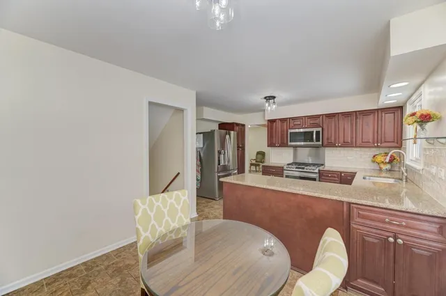 a kitchen with stainless steel appliances granite countertop a stove top oven a sink dishwasher and white cabinets with wooden floor