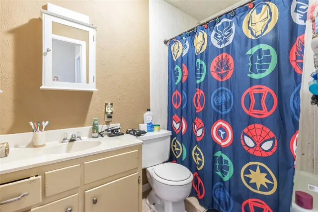 a bathroom with a granite countertop toilet sink and mirror
