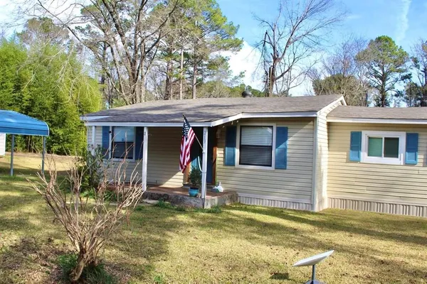 a view of a house with small yard plants and large tree