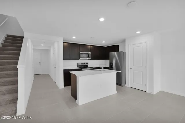 a view of a kitchen with a sink and dishwasher a refrigerator with white cabinets
