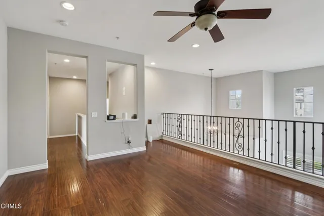 a view of a hallway with wooden floor and chandelier fan