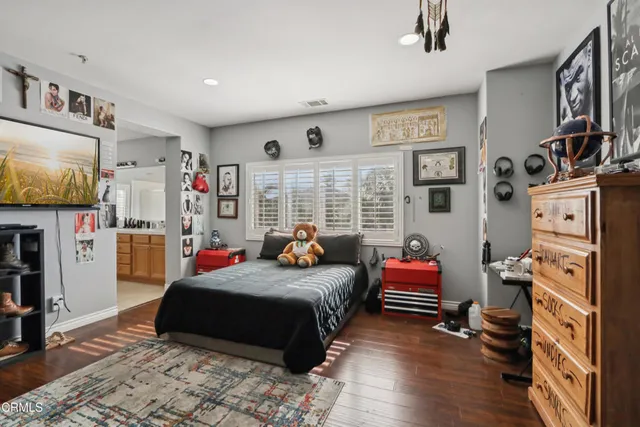 a bedroom with furniture a flat screen tv and a window