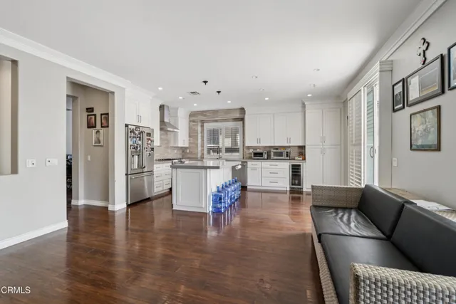a living room with stainless steel appliances furniture refrigerator and a kitchen view