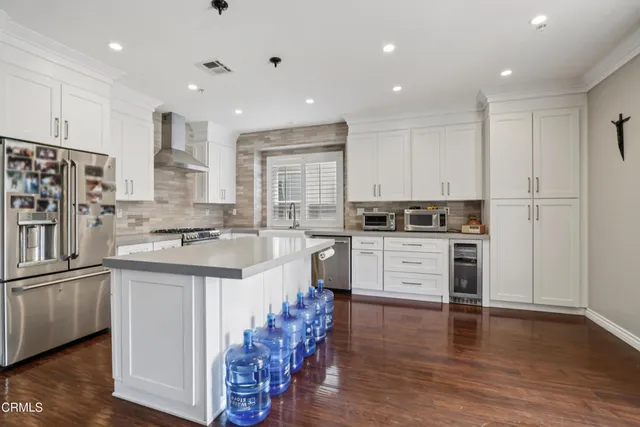a kitchen with stainless steel appliances granite countertop a white cabinets and wooden floor