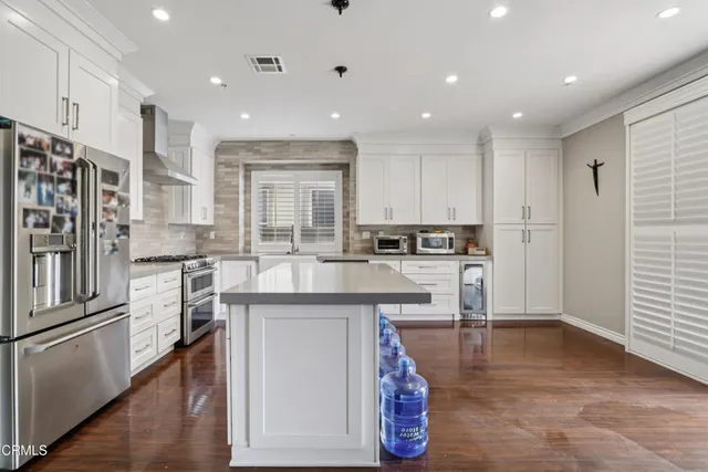 a kitchen with stainless steel appliances granite countertop a refrigerator and a stove top oven