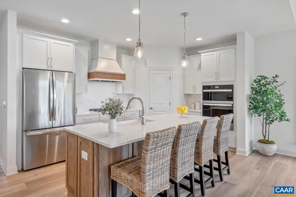 a kitchen with stainless steel appliances granite countertop a refrigerator a sink a stove and chairs with wooden floor