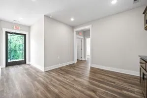 a view of an empty room with wooden floor and a window