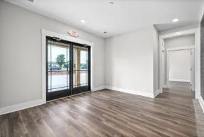 a view of an empty room with wooden floor and a window