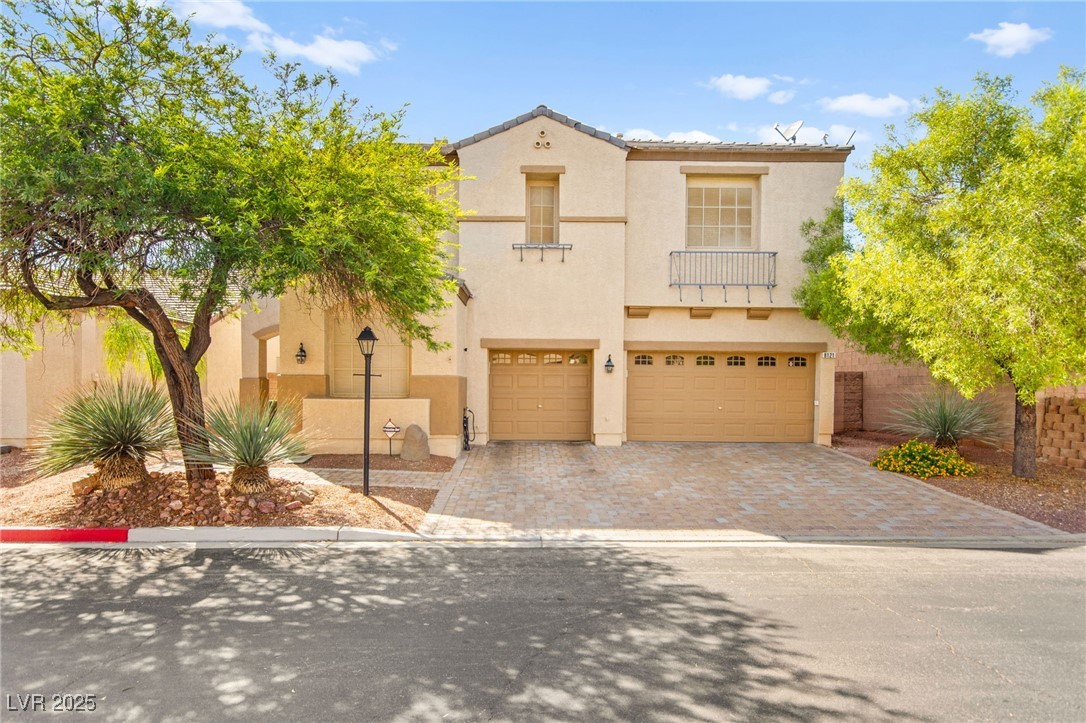 Mediterranean / spanish home featuring a garage, decorative driveway, stucco siding, and a balcony