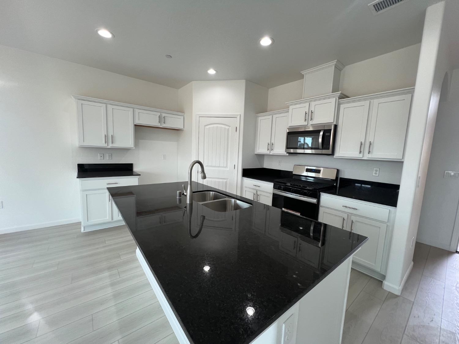 1502 Concord Way Dinuba, CA 93618 - Photo 8 of 12 a kitchen with kitchen island a white counter top space cabinets and stainless steel appliances