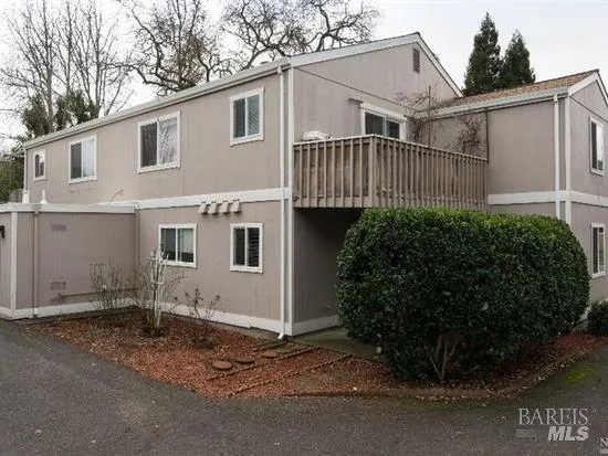 a view of a white house with a small yard and large parking space