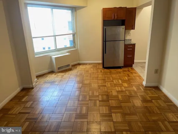 a view of a refrigerator in kitchen and an empty room