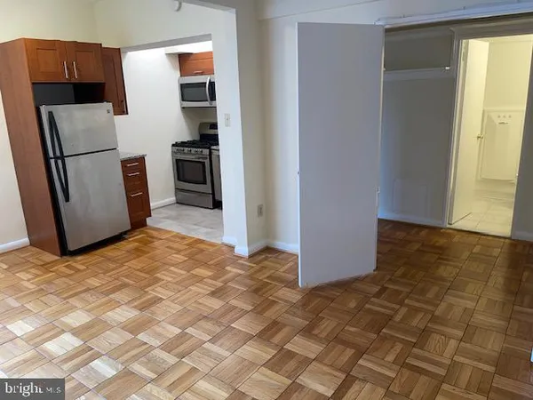 a view of a refrigerator in kitchen and an empty room