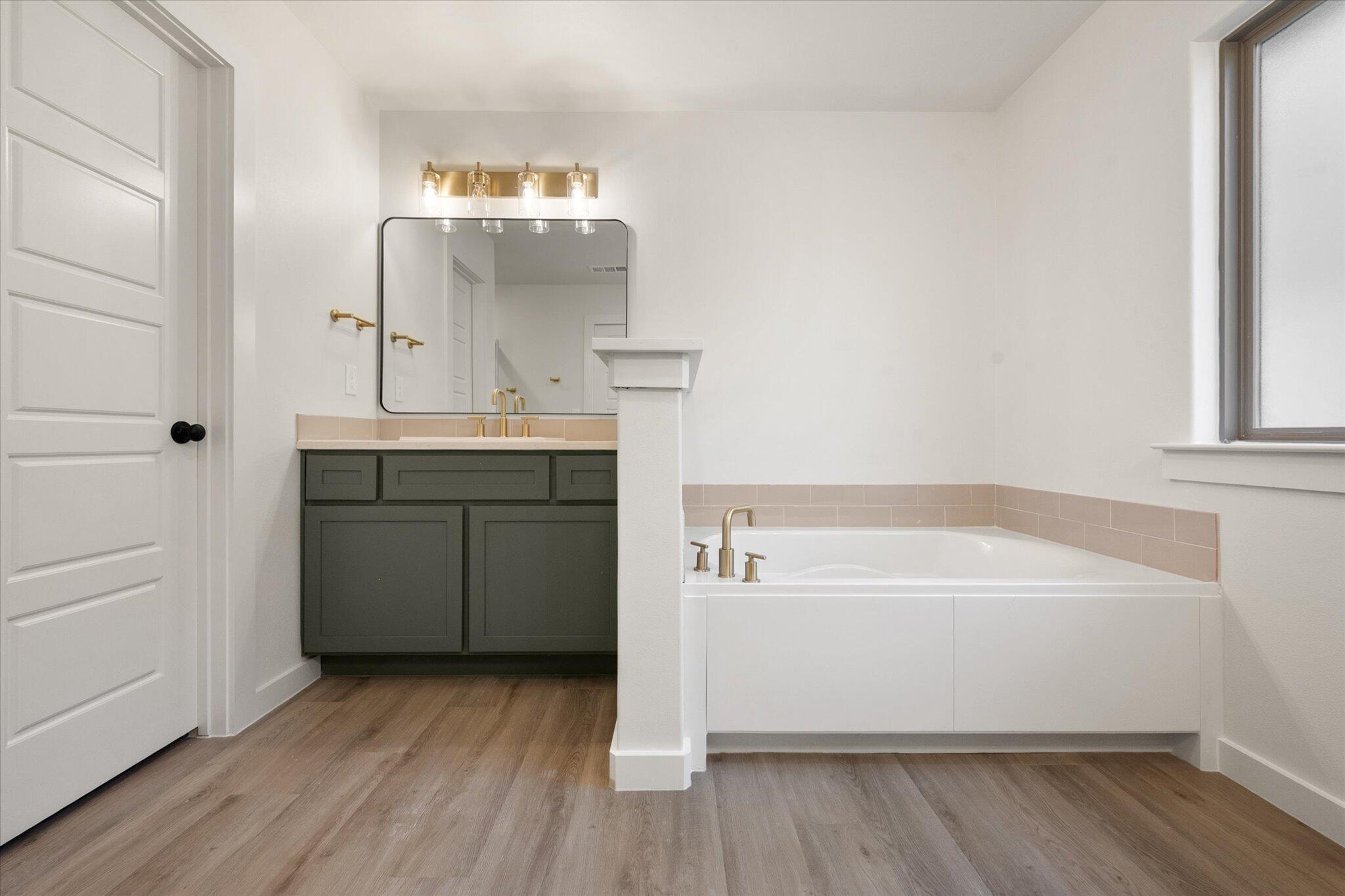 7004 16th Street Lubbock, TX 79416 - Photo 16 of 25 a bathroom with a tub sink and mirror