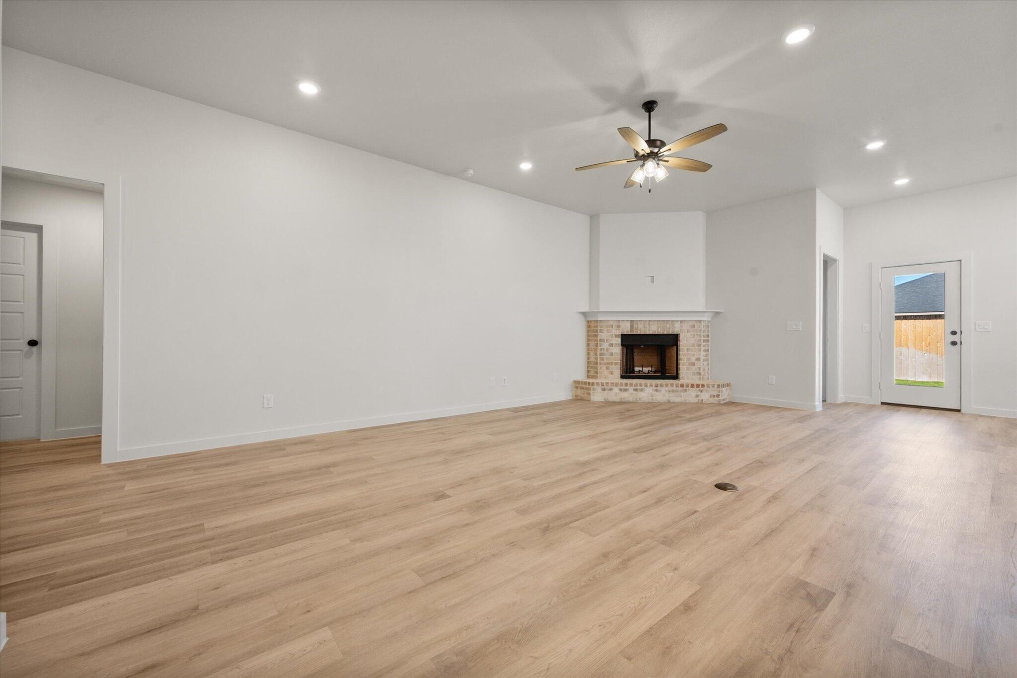 7004 16th Street Lubbock, TX 79416 - Photo 4 of 25 an empty room with wooden floor ceiling fan and kitchen view