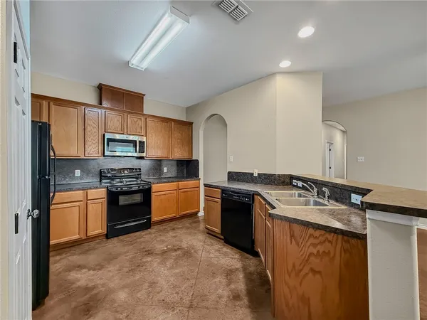 a large kitchen with stainless steel appliances granite countertop a stove refrigerator sink and cabinets