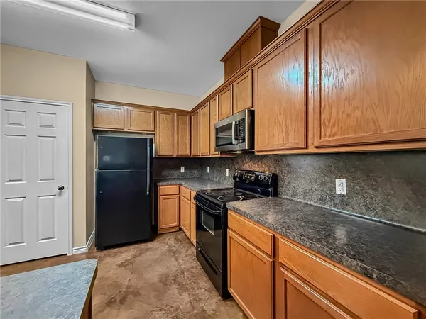 a kitchen with stainless steel appliances granite countertop a refrigerator a stove a sink and dishwasher with wooden cabinets