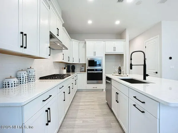 a large kitchen with stainless steel appliances granite countertop a sink a stove and cabinets