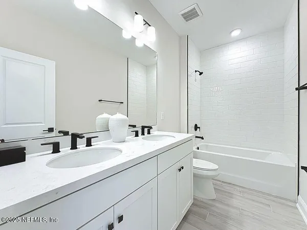 a bathroom with a double vanity sink toilet mirror and bathtub