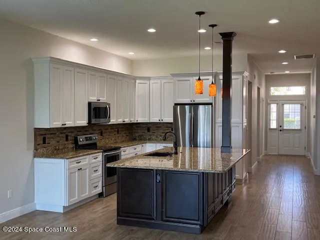 a kitchen with stainless steel appliances granite countertop a refrigerator a stove a sink and a microwave