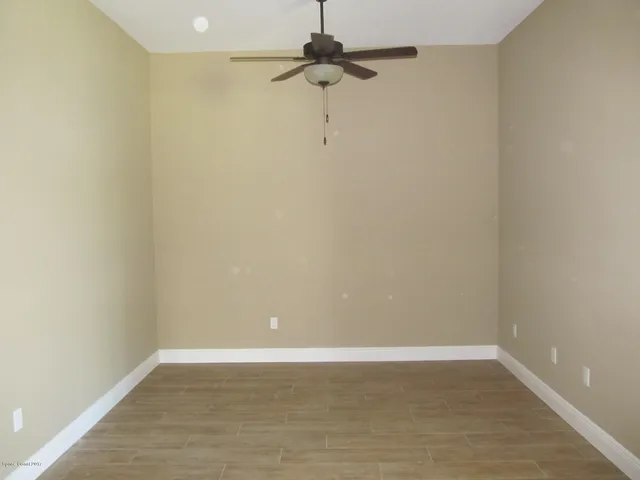 a view of a small space with wooden floor and fan
