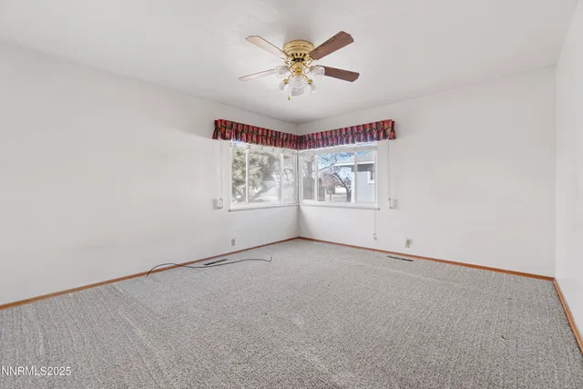 an empty room with window and ceiling fan