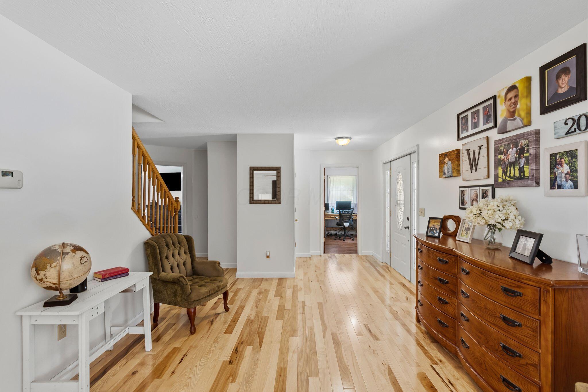 10446 Rich Hollow Road Southwest Lancaster, OH 43130 - Photo 37 of 83 Spacious entry area with light wood-finish flooring, white walls, a visible staircase with wood banister, and a white front door with decorative glass