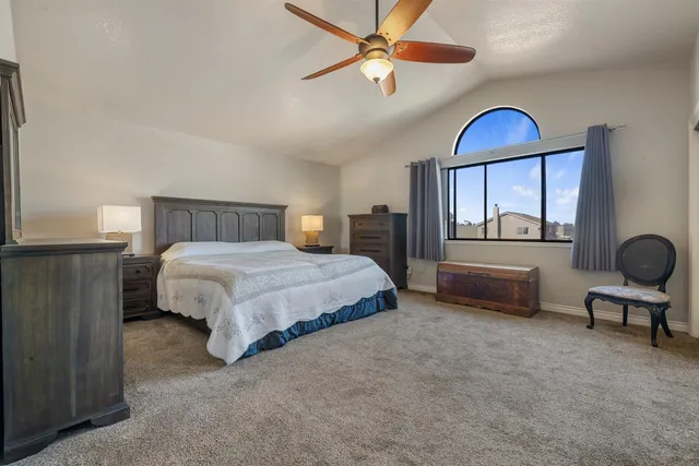 a spacious bedroom with a bed and ceiling fan