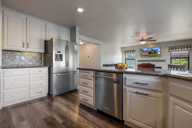 a kitchen with stainless steel appliances kitchen island granite countertop a table chairs and a refrigerator