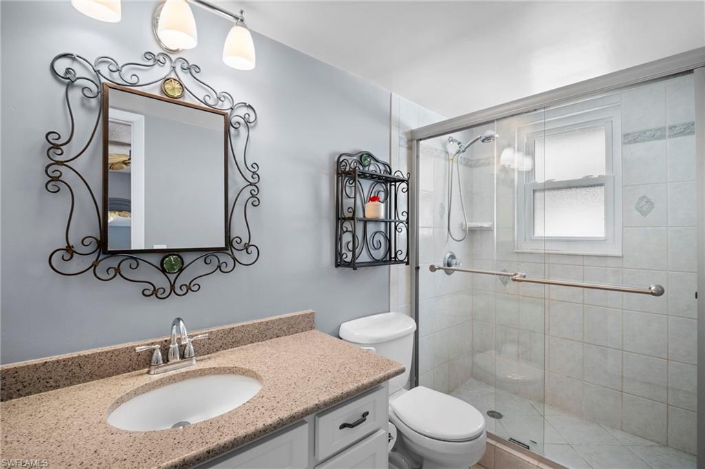 1155 Sandpiper Street, Unit G2 Naples, FL 34102 - Photo 6 of 8 a bathroom with a granite countertop sink toilet a mirror and shower