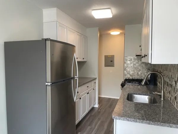 a kitchen with granite countertop a refrigerator and a sink