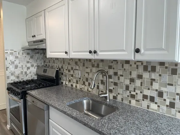 a kitchen with granite countertop a sink a stove and cabinets
