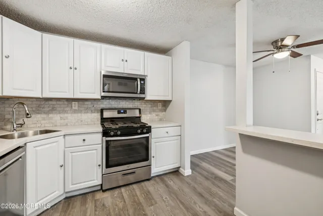 a kitchen with stainless steel appliances white cabinets and a stove top oven