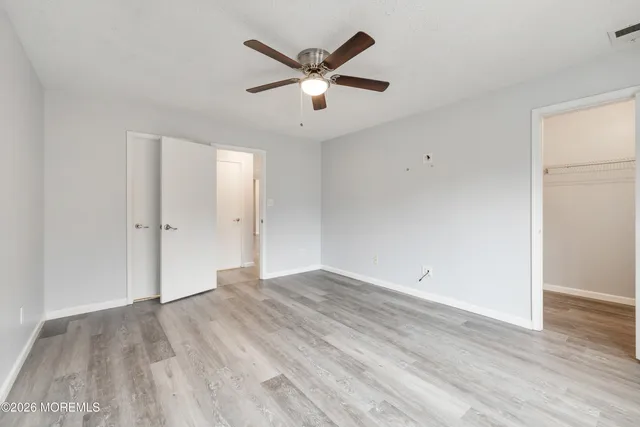 an empty room with wooden floor and ceiling fan