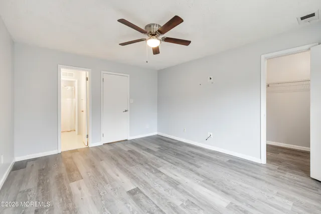 an empty room with wooden floor and ceiling fan
