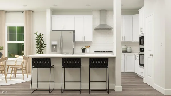 a kitchen with stainless steel appliances granite countertop a stove a refrigerator white cabinets and wooden floor