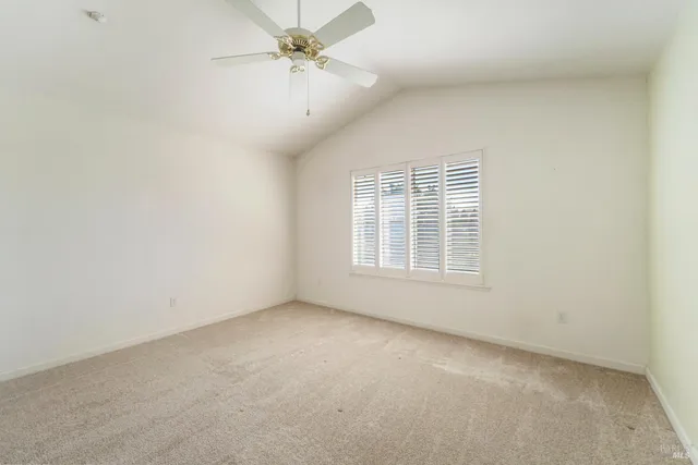 an empty room with a ceiling fan and a window